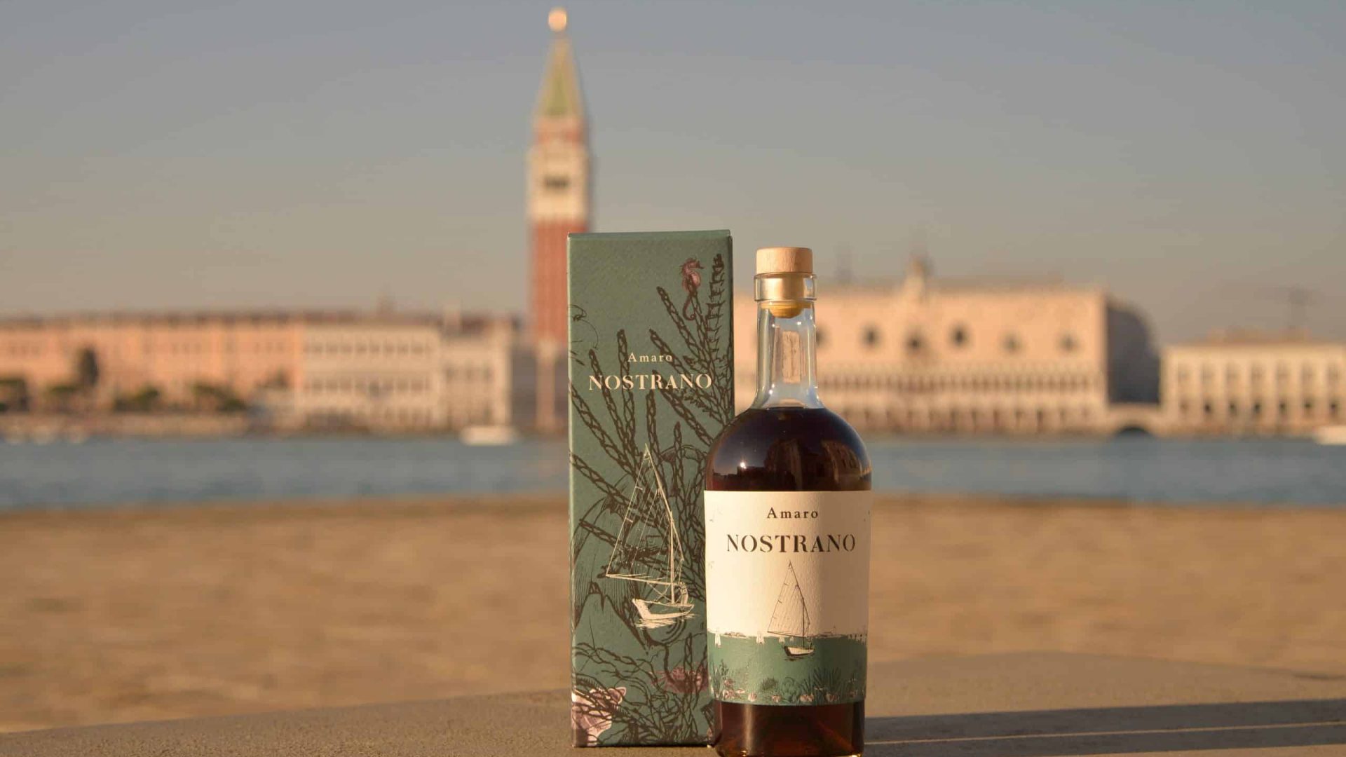 Amaro Nostrano bottiglia e confezione con panorama Venezia e Campanile San Marco al tramonto